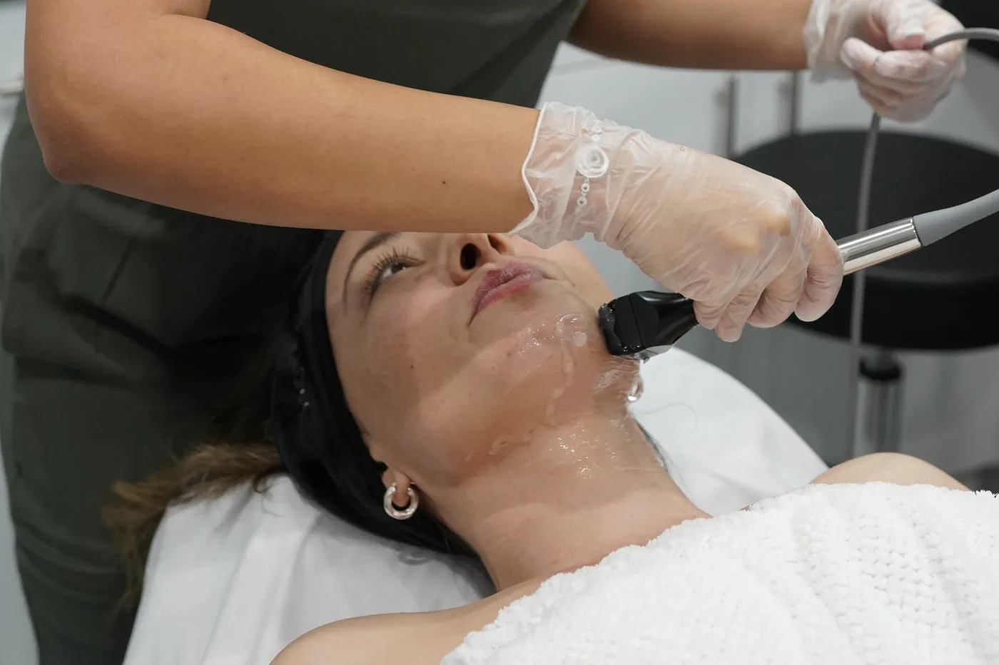 An AWE provider gliding the Forma handpiece along a guest's jaw and cheek